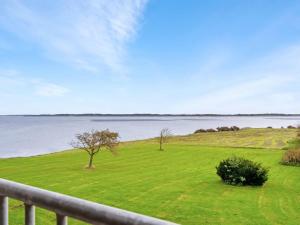 a green field with a fence and a view of the water at Holiday Home Thorge - 75m to the inlet by Interhome in Struer
