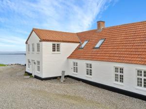 a white house with an orange roof next to the water at Holiday Home Thorge - 75m to the inlet by Interhome in Struer