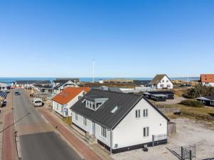 a white house with a black roof next to a road at Holiday Home Thilla - 100m from the sea by Interhome in Thisted