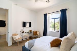 Un dormitorio con una cama y un escritorio y una ventana. en Designer Desert Condo! Poolhot Tub Dogs Welcome!, en La Quinta