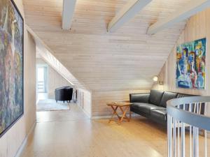 a living room with a black couch and wooden walls at Holiday Home Gertrudis - 2km to the fjord by Interhome in Frøstrup