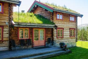 a log cabin with a deck and chairs in front of it at Øvre Nordli Rondane Utleie Sollia Friluftsliv in Sollia