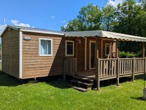 een houten hut met een veranda en een terras bij Camping Chantecler in Luchon