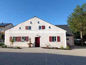 a white house with red shutters and a red door at Chalet Bauer - 5 Sterne Ferienhaus im Altmühltal in Beilngries
