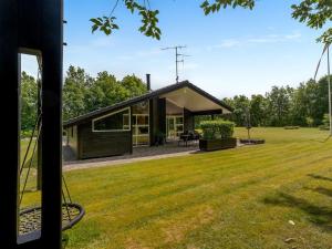 a house with a black roof on a grass field at Holiday Home Yorrit - 500m to the fjord by Interhome in Højslev +22 photos