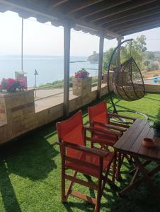 een patio met stoelen, een tafel en een schommel bij Lia Apartment Sea View in Nea Fokea