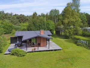 a small house with a black roof in a field at Holiday Home Skjold - 600m from the sea by Interhome in Grenå