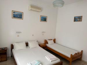duas camas em um quarto com paredes brancas em Helena & Giorgio Rooms Cfu em Agios Georgios