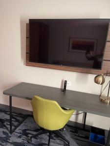 een bureau met een gele stoel en een televisie aan de muur bij Fairfield Inn and Suites Dalton, GA in Dalton