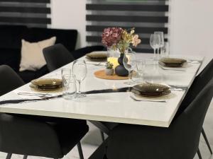una mesa con platos y vasos y un jarrón de flores en Short Stay Expozitiei, en Baia Mare