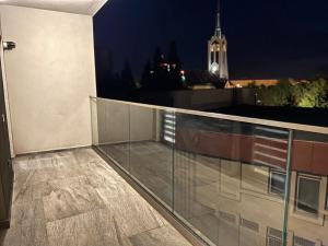 Un balcón de un edificio por la noche con una torre de reloj. en Short Stay Expozitiei, en Baia Mare