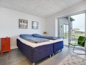 ein Schlafzimmer mit einem blauen Bett und einem grünen Stuhl in der Unterkunft Holiday Home Anniina - 200m from the sea by Interhome in Knebel