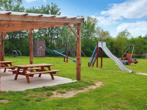 Un parque infantil con dos mesas de picnic y un tobogán. en Holiday Home Anselm by Interhome, en Fårvang