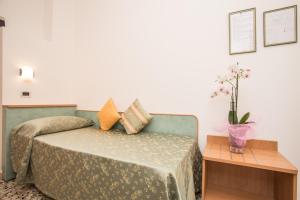 1 dormitorio con 1 cama y 1 mesa con flores en Hotel Oregon, en Rímini