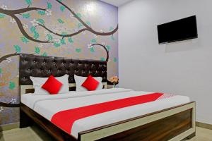 een slaapkamer met een bed met rode kussens en een televisie bij Hotel O Atharv Palace in Prayagraj +22 foto's
