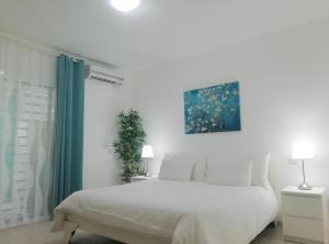 プンタ・カナにあるCondo 1bdr 1bth garden viewの白いベッドと壁に絵画が飾られたベッドルーム1室