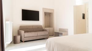 a bedroom with a couch and a television on a wall at Principe Boemondo Luxury Room in Canosa di Puglia