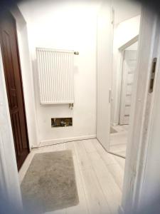 a white hallway with a door and a rug at Przytulna kawalerka in Prószków