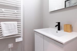 une salle de bain blanche avec un lavabo et un miroir dans l'établissement L'Ile Barbe - Studio cosy avec mezzanine, à Caluire-et-Cuire