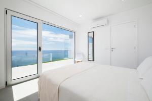 a bedroom with a white bed and a large window at Beira Da Rocha in Ponta Delgada