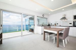 a kitchen with a wooden table and a large window at Beira Da Rocha in Ponta Delgada