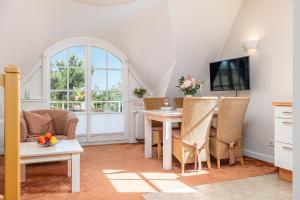 un soggiorno con tavolo, sedie e TV di Dünentraum a Neuhaus