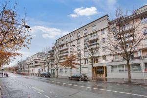 a large white building with cars parked in front of it at Beau F2, Paris Stade de France, Jacuzzi, Parking in Saint-Denis