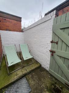 two chairs sitting next to a brick wall with a door at Liverpool Rose House Stylish 3 Bed Near Anfield and Goodison Park in Liverpool