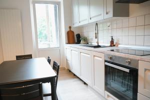 cocina con armarios blancos, mesa y fregadero en Lichtdurchflutete Altbauwohnung direkt an der Oder, en Frankfurt de Oder