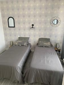 a bedroom with two beds and a wall with two mirrors at Les Sables d'Olonne, Les Présidents, charmant appartement lumineux, plage 150 m. in La Rudelière