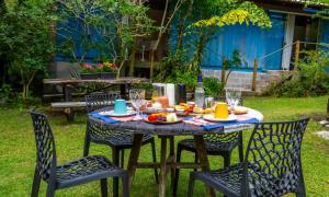 an outdoor table with chairs and food on it at Eco Manguinhos Pousada Container in Serra