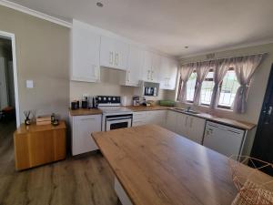 a kitchen with white cabinets and a wooden table at Peaceful, Cheerful, Family Friendly 3Bedroom house in Edgemead