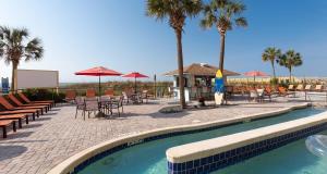 een zwembad met stoelen, tafels en palmbomen bij Best Western Ocean Sands Beach Resort in Myrtle Beach