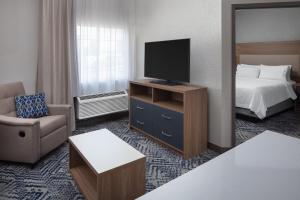 a hotel room with a bed and a television at Candlewood Suites St. Robert by IHG in Saint Robert