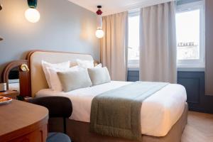 ein Hotelzimmer mit einem Bett mit weißen Laken und Kissen in der Unterkunft Grand Hotel Saint Michel in Paris