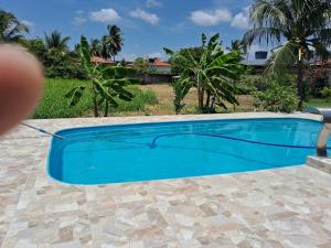 a blue swimming pool in front of a house at Casas Aluguel Temporada Pousada Village Maçarico in Salinópolis
