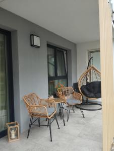 a patio with chairs and a table and a swing at Apartament -Podczele in Kołobrzeg