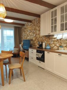 a kitchen with white cabinets and a stone wall at Apartament -Podczele in Kołobrzeg
