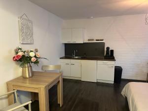 a room with a kitchen and a table with a vase of flowers at Studio close to Maastricht in Cadier en Keer