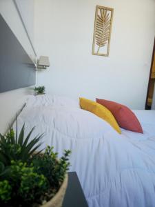 a white bed with two colorful pillows on it at Apartment 4-6 personnes avec Piscine Demeure De la Massane in Argelès-sur-Mer
