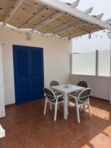 a table and chairs in a room with a blue door at Apartamentos Burgao in Caleta de Sebo