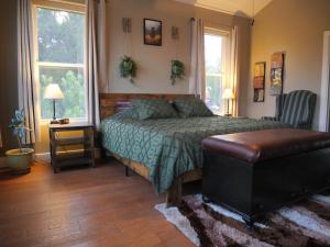 a bedroom with a bed and a chair and windows at Hilltop Saltwater Pool and Hot Tub in Dripping Springs
