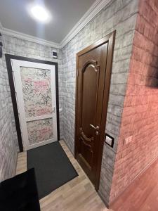 a hallway with a door and a brick wall at Вип Квартира посуточно in Shakhtīnsk
