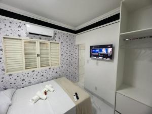 a bedroom with a bed and a tv on the wall at pousada automatica 3 santiago in Uberlândia
