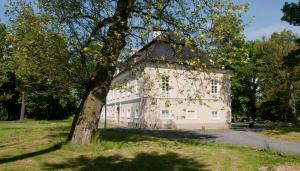 un gran edificio blanco con un árbol en el primer plano en Zámek Jeseník Nad Odrou en Jeseník nad Odrou