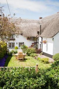 a white house with a table and chairs in the yard at Farmhouse Cottage in Sidmouth