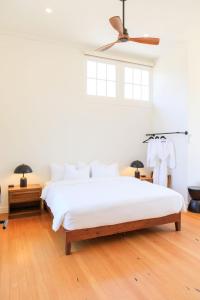 a bedroom with a white bed and a ceiling fan at The Historic Schoolhouse Inn in Trinidad
