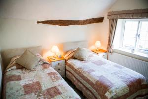 a bedroom with two beds next to a window at Farmhouse Cottage in Sidmouth