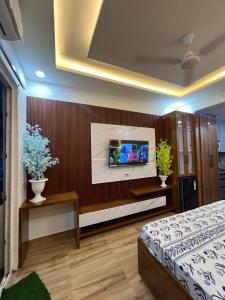 a bedroom with a bed and a tv on a wall at Anmolairbnb in Greater Noida