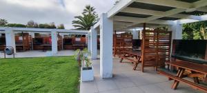 a patio with wooden tables and chairs and a lawn at Avenida del Mar Condominio Oceanic in La Serena